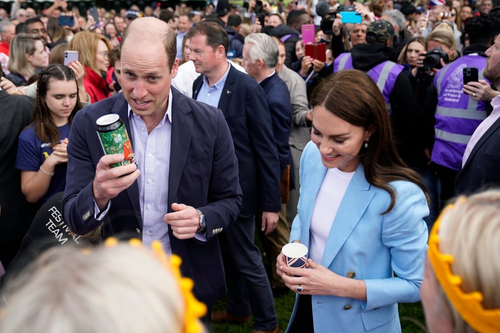 El Príncipe William, Príncipe de Gales, de Gran Bretaña, sostiene una lata de cerveza orgánica para la coronación, con Kate, Princesa de Gales, durante una reunión itinerante con miembros del público en Long Walk, cerca del Castillo de Windsor.