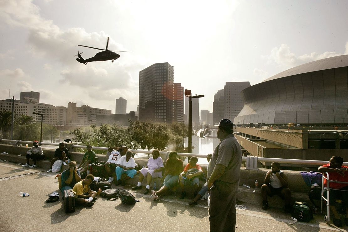 La gente busca un terreno más elevado en la Interestatal 90 mientras un helicóptero se prepara para aterrizar en el Superdomo de Nueva Orleans el 31 de agosto de 2005.