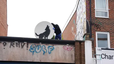 PA Alguien retira una antena parabólica con una obra de arte de Banksy