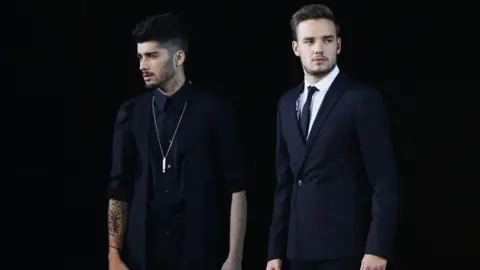 Getty Images Zayn Malik y Liam Payne en el escenario con un fondo negro, ambos con trajes negros.